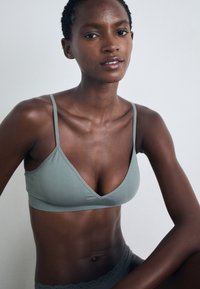 Bralet u mint zelenoj boji, trokutastog oblika, s tankim trakama, s glatkom teksturom i minimalističkim dizajnom. Jednostavna, bešavna izrada.