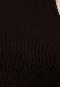 Top sin mangas negro con perfilado acanalado que presenta finas líneas horizontales, fabricado en un tejido suave con un diseño ajustado. Sin herrajes o embellishments visibles.