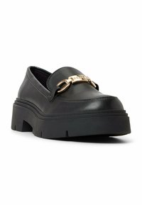 Svart läderloafers med rundad tå, tjock gummiplattform och gyllene detaljer över framfoten. Slät ytstruktur och modern design.