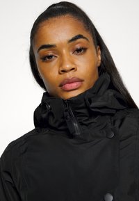 Czarna kurtka z wysokim kołnierzem, zamek błyskawiczny z przodu i napami. Wykonana z gładkiego, wodoodpornego materiału o nowoczesnym, eleganckim designie.