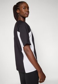 Zwart-wit T-shirt met korte mouwen en een relaxed fit, met een kleurblok ontwerp en een ronde halslijn. Zacht katoen materiaal.