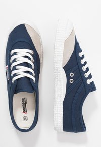 Marineblaue Leinensneaker mit beigen Akzenten,weißer Gummisohle,runder Zehenpartie und weißen Schnürsenkeln. Verfügt über Ösen und eine strukturierten Gummisohle.