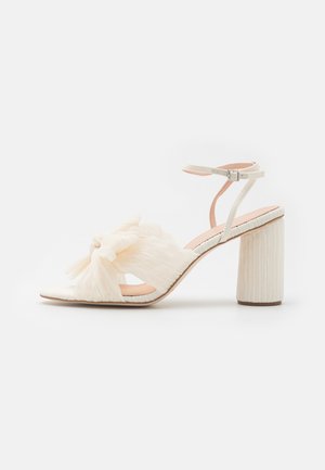 Sandalo con tacco alto da donna in crema. Presenta un dettaglio a fiocco testurizzato, una punta aperta e un tacco quadrato spesso con un design rigato. Cinturino regolabile alla caviglia.
