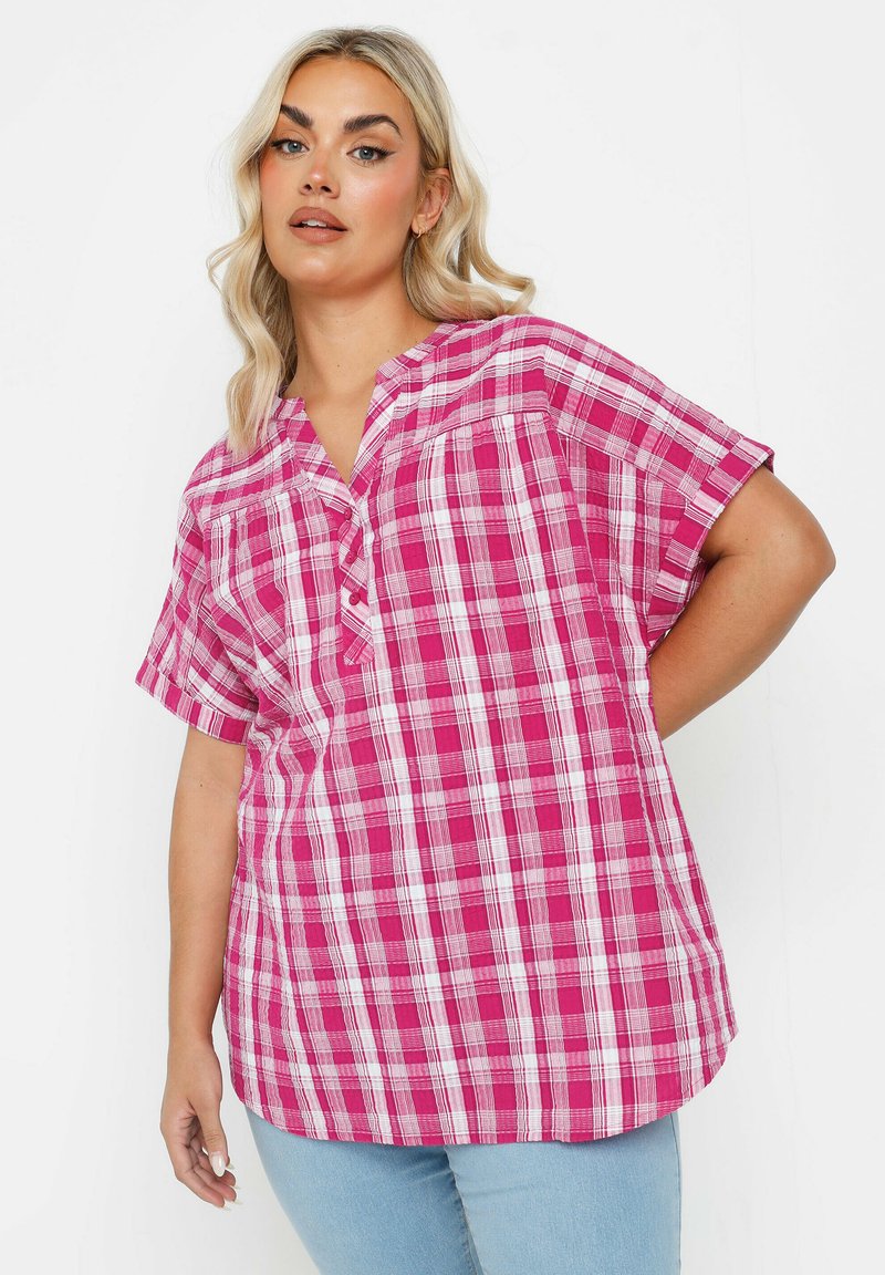 Blusa a maniche corte a quadri rosa con scollatura a V, caratterizzata da linee bianche e rosa scuro. Tessuto leggero con una vestibilità comoda.