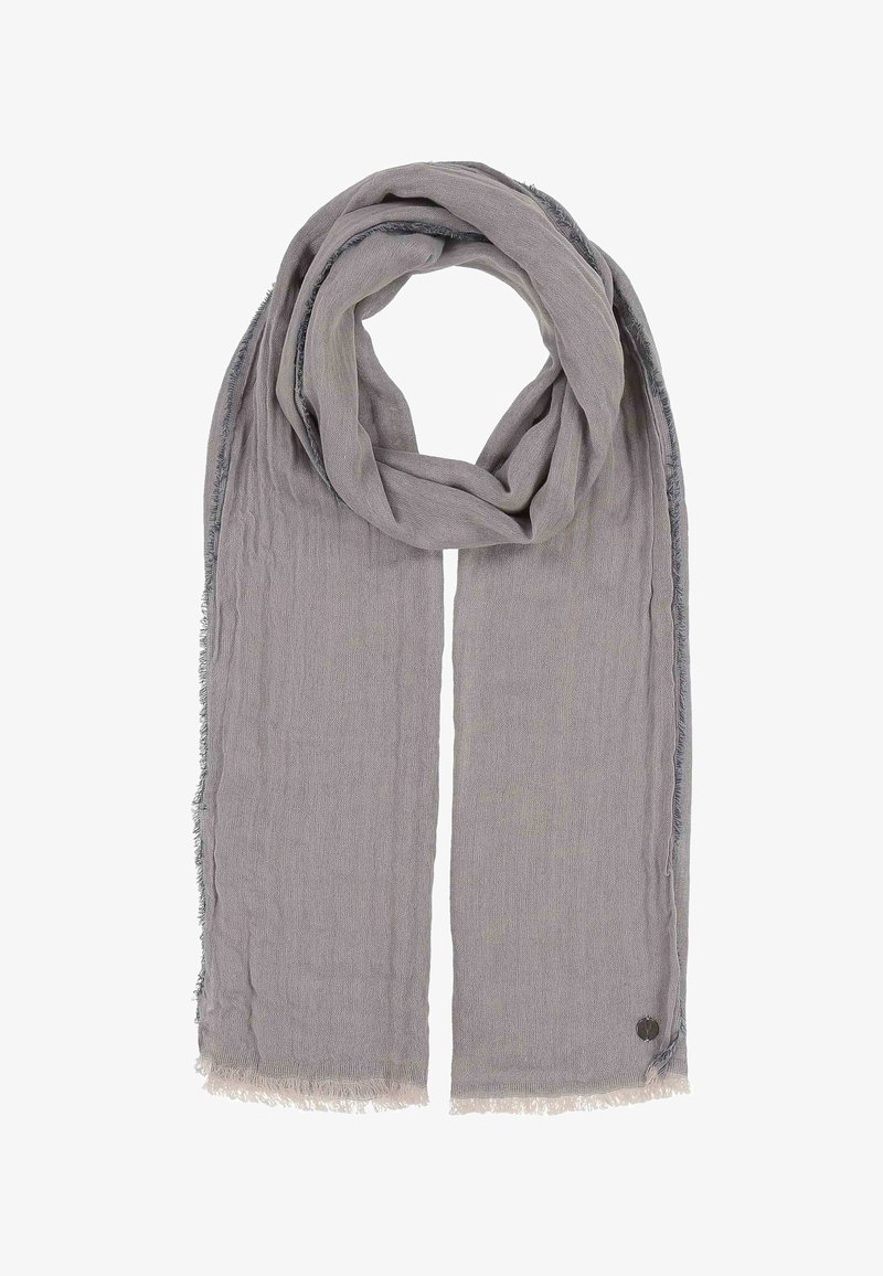 Écharpe rectangulaire grise claire douce, pliée avec des bords à franges et un petit logo métallique rond près d'un coin.