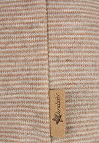 Close-up of beige and white striped knit fabric with a small tan leather tag embossed with a star and the word "Stonatelier."