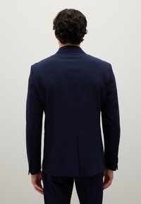 Blazer blu navy su misura con una texture liscia, fessura singola sul retro e maniche su misura con dettagli in bottone.