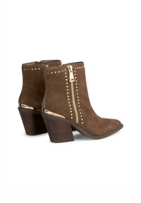 Braune Wildleder-Stiefeletten mit einem goldenen Reißverschluss, Nietenverzierungen an der Seite und einem Blockabsatz, mit einem spitzen Zehendesign.
