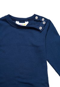 Tums navy zila gara piedurkne krekls, izgatavots no mīksta auduma, ar apaļu kaklu un trīs spiedpogu izvietojumu kreisajā plecā.