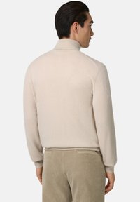 Pull en laine et cachemire beige, col roulé, à manches longues et col côtelé. Texture lisse avec une silhouette ajustée.