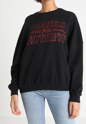 Zwarte oversized sweatshirt van zachte stof, met op de voorkant in rode tekst "THANKS FOR NOTHING". Ribboorden bij de mouwen en onderkant.