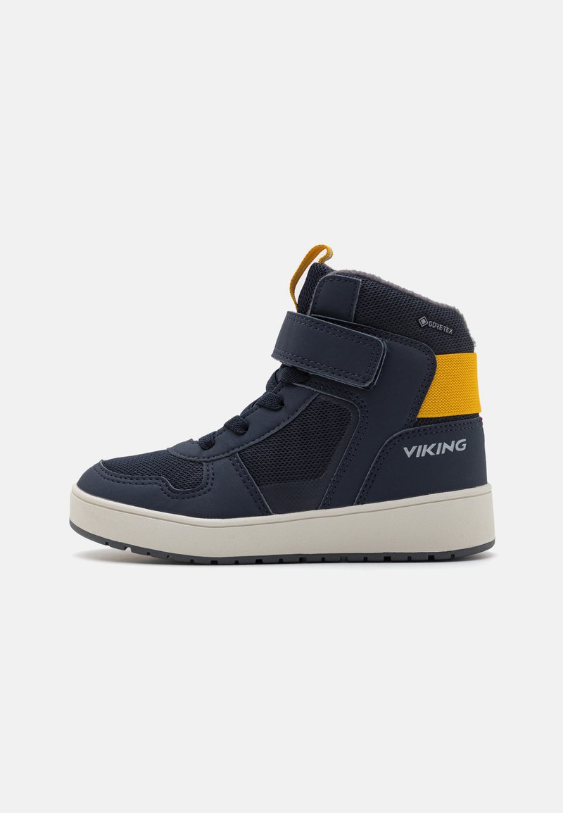 Bottines haute en bleu marine imperméable avec une sangle en Velcro, à lacets sur le devant et semelle beige. Présente des panneaux en maille et des accents jaunes.