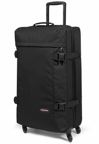 Maleta negra con ruedas, exterior de tela suave, mango retráctil y dos correas laterales para un cierre seguro. Presenta el logo de Eastpak.