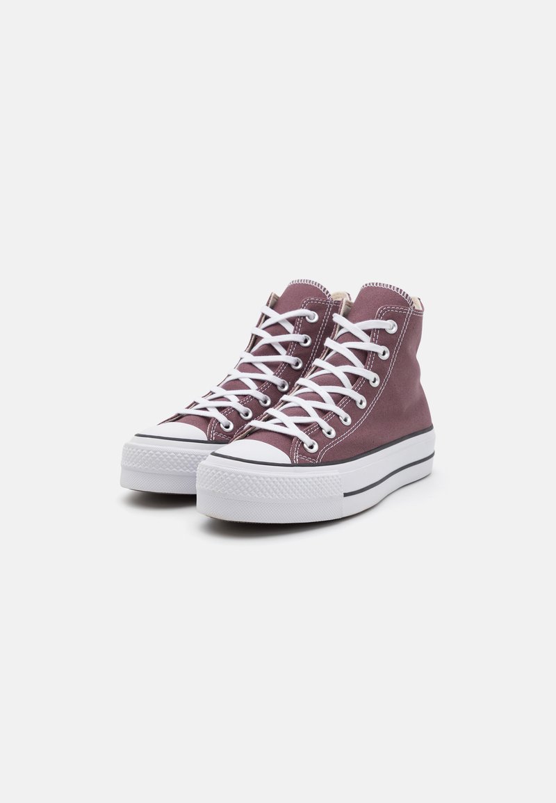 Sneakers alte in tela viola con lacci bianchi, suola in gomma e punta rinforzata. Presentano una striscia nera lungo la suola e dettagli di cucitura bianca.