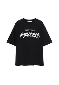 Musta ylisuuri t-paita lyhyillä hihoilla. Siinä on valkoista tekstiä: "LVDA GAGA" "MAYHEM" -sanan yläpuolella kuluneessa, paksussa fontissa. Puuvillamateriaali.
