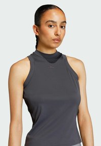 Tamna siva bez rukava atletska majica s visokim vratom, izrađena od glatkog materijala; sadrži suptilni logotip na prsima.