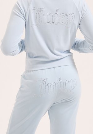 Survêtement en velours bleu clair vu de l'arrière avec le texte "Juicy" en strass sur la veste et le pantalon.