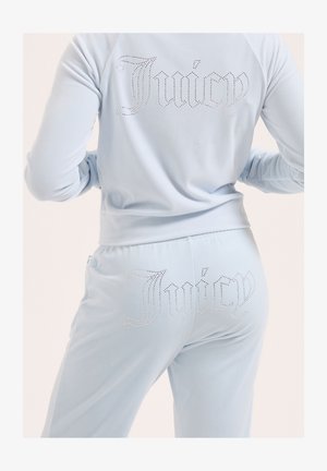 Survêtement en velours bleu clair vu de l'arrière avec le texte "Juicy" en strass sur la veste et le pantalon.