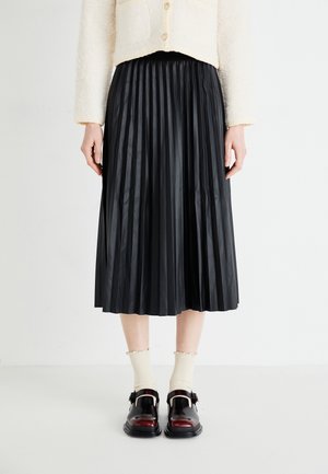 Black pleated midi skirt made of lightweight fabric, featuring an elastic waistband. Paired with black and burgundy shoes and cream socks.