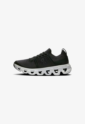 Sport shoes in black mesh material with a textured surface, featuring a thick white wavy sole and black accents. Laces and heel tab included.