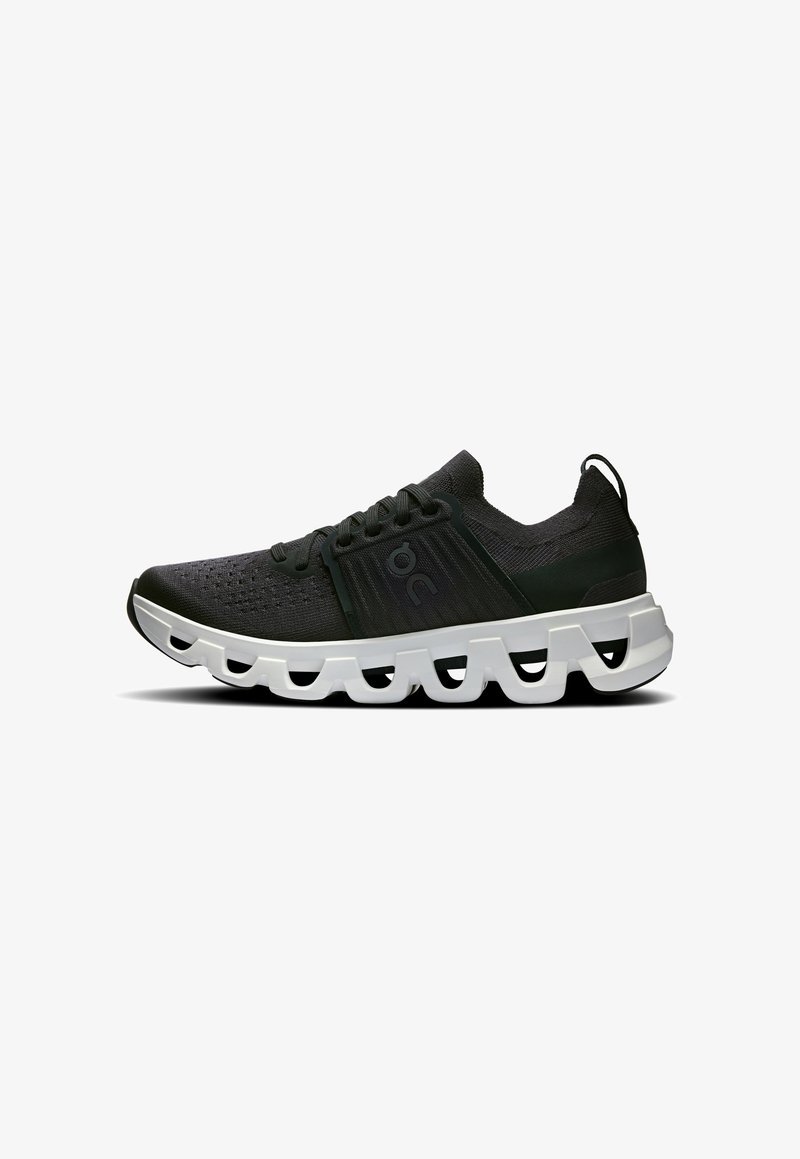 Baskets en maille noire avec une surface texturée, dotées d'une épaisse semelle ondulée blanche et d'accents noirs. Lacets et languette au talon inclus.