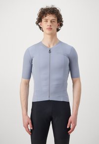 Maillot de cyclisme à manches courtes en bleu clair, avec une fermeture éclair à l'avant et un tissu texturé. Assorti avec un short de cyclisme noir, au design ajusté.