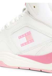 Białe skórzane sneakersy z różowymi akcentami, z prostokątnym logo z napisem "TOMMY JEANS". Teksturowana gumowa podeszwa i sznurówki.