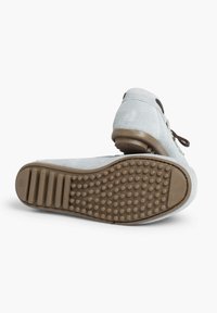 Pantofii din suede de culoare albastră deschisă, cu vârf rotund, șireturi maro și talpă din cauciuc texturat, dotată cu puncte de aderență și toc plat.