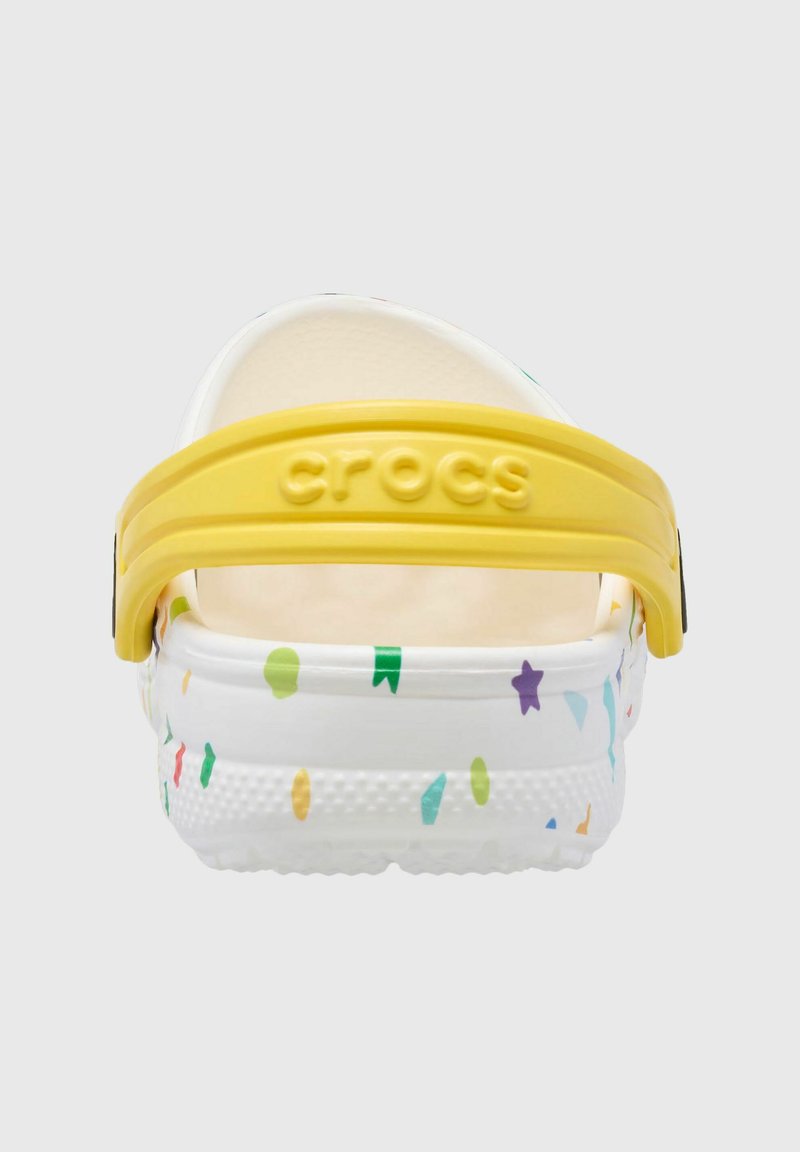 Weiße Crocs mit bunten, verstreuten Sternen- und Formmustern. Verfügt über einen gelben Fersenriemen mit eingeprägtem "CROCS". Texturierte Sohle für Grip.