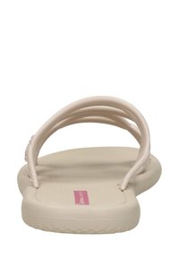 Beige gummiklippklap sandal med dubbla tunna remmar och en platt sula, sedd framifrån.