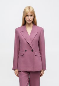 Zweireihiger Blazer aus weichem, violettem Stoff, mit gro�ßen Revers, zwei Vordertaschen und schwarzen Knöpfen zum Schließen.