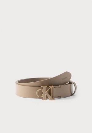 Cinturón de cuero beige con hebilla dorada "cK" y sutil marca de Calvin Klein en la punta, enrollado sobre un fondo blanco.
