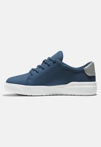Zapatillas deportivas para hombre en material sintético azul marino, con un corte superior liso, suela de goma blanca y un acento gris en el talón. Diseño con cordones.