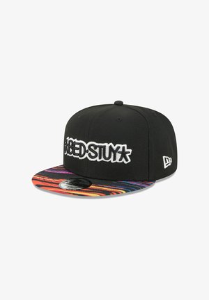Schwarze Snapback-Kappe mit weißem, gesticktem "BED-STUY"-Logo und einem lebendigen, mehrfarbigen Muster am gebogenen Schirm mit geschwungenen Linien.