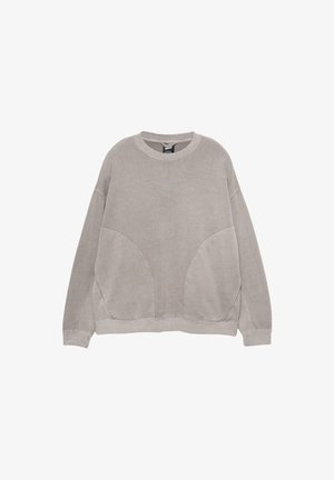 Sweatshirt oversize gris clair, avec un col rond, des épaules tombantes et des coutures latérales courbées. Fait en matériau en coton doux.