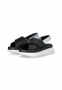 Black and silver slide sandals with a thick white sole. Features a textured strap with a logo and an open toe design. Soft material.