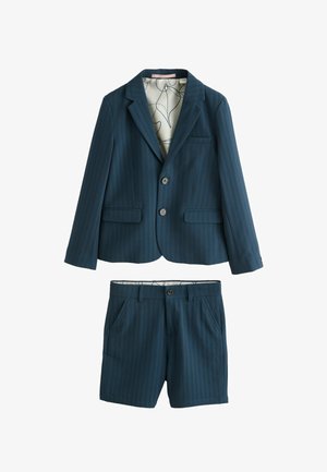 Tumesinise tekstuuriga kahest osast koosnev ülikonnakomplekt, millel on kahe nupuga bleiser ja sobivad tailoritud püksid, sisemise voodri abstraktse joonemustriga.