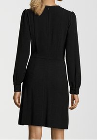 Abito lungo nero a maniche lunghe con vita aderente, zip sul retro e polsini con bottoni. Tessuto morbido con una sottile texture e linee pulite.