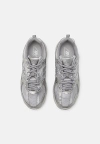 Zapatillas de running plateadas con superposiciones de malla y sintético, que cuentan con cordones planos, lengüeta acolchada y detalles de logotipo a los lados.