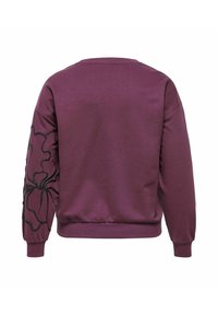 Sudadera morada con cuello redondo, que presenta un gran diseño floral negro en la manga izquierda y puños y dobladillo acanalados. Textura suave.