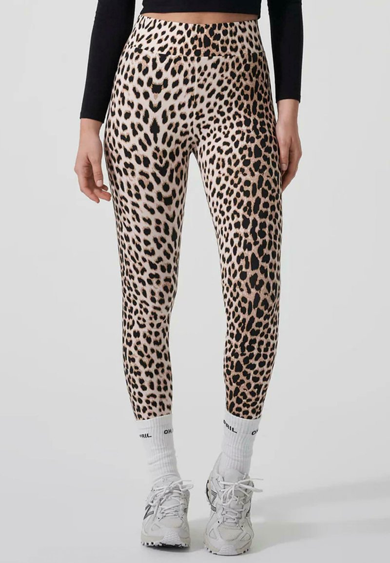 Leopard print leggings with a high waist, featuring a smooth, stretchy fabric in beige and black tones, paired with white athletic socks and shoes.