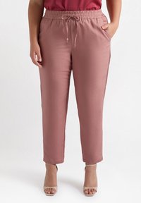 Jasnoróżowe spodnie z elastycznym paskiem, regulowanym sznurkiem, bocznymi kieszeniami i prostym krojem nogawek.