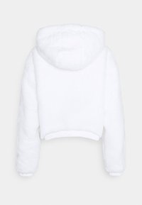 Veste blanche courte en tissu doux et texturé, avec une capuche et des manches à poignets élastiques. Le dos a une finition lisse et soignée.