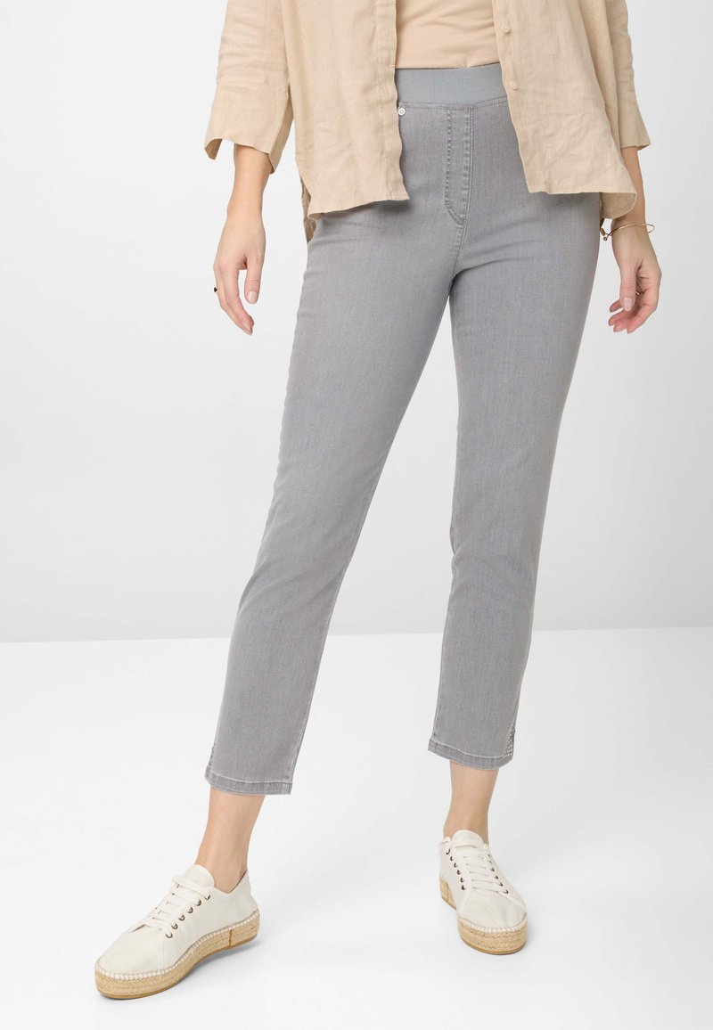 Grijze aansluitende broek met een gladde textuur, hoge tailleband en enkellange stijl, gecombineerd met witte veterschoenen.