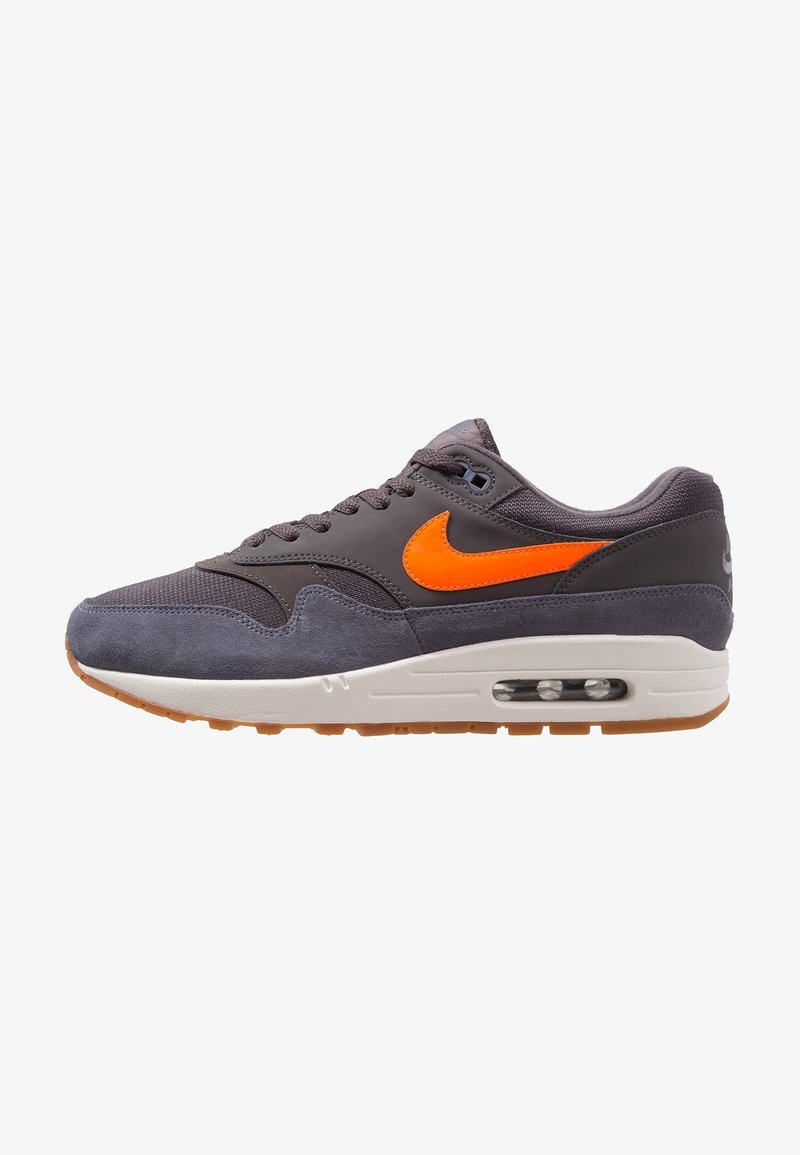 Nike tenisky v šedé a oranžové barvě. Mají svrchní část vyrobenou ze směsi zamaku a síťoviny, kulatou špičku, šněrování a viditelnou vzduchovou bublinu v podešvi.