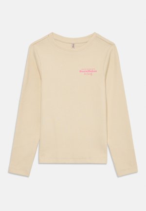 Långärmad ribbad skjorta i beige med rundad hals och rosa tryckt text "Kom ihåg Snöflingor & Godis" på bröstet.
