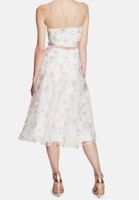 Šaty bez ramínek z lehkého, průsvitného materiálu; pastelové květiny na bílém pozadí; přiléhavá korzetová část, splývavá A-čková sukně; saténový pás.