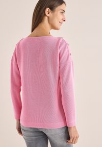 Rosa, gerippter Strickpullover mit weitem Ausschnitt und dekorativen Knöpfen an der Schulter, mit langen Ärmeln und lässiger Passform.