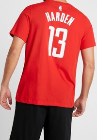 Czerwona koszulka do koszykówki z krótkim rękawem, z dużym białym nadrukiem "HARDEN" oraz numerem "13" na plecach, z okrągłym dekoltem.