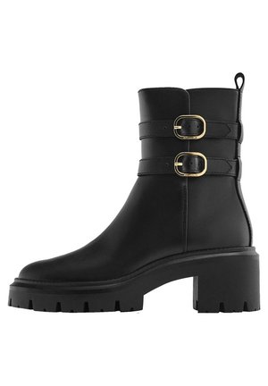 Bottines noires en cuir avec deux sangles de boucle horizontales. Elles sont dotées d'un talon épais et d'une semelle en caoutchouc texturé.